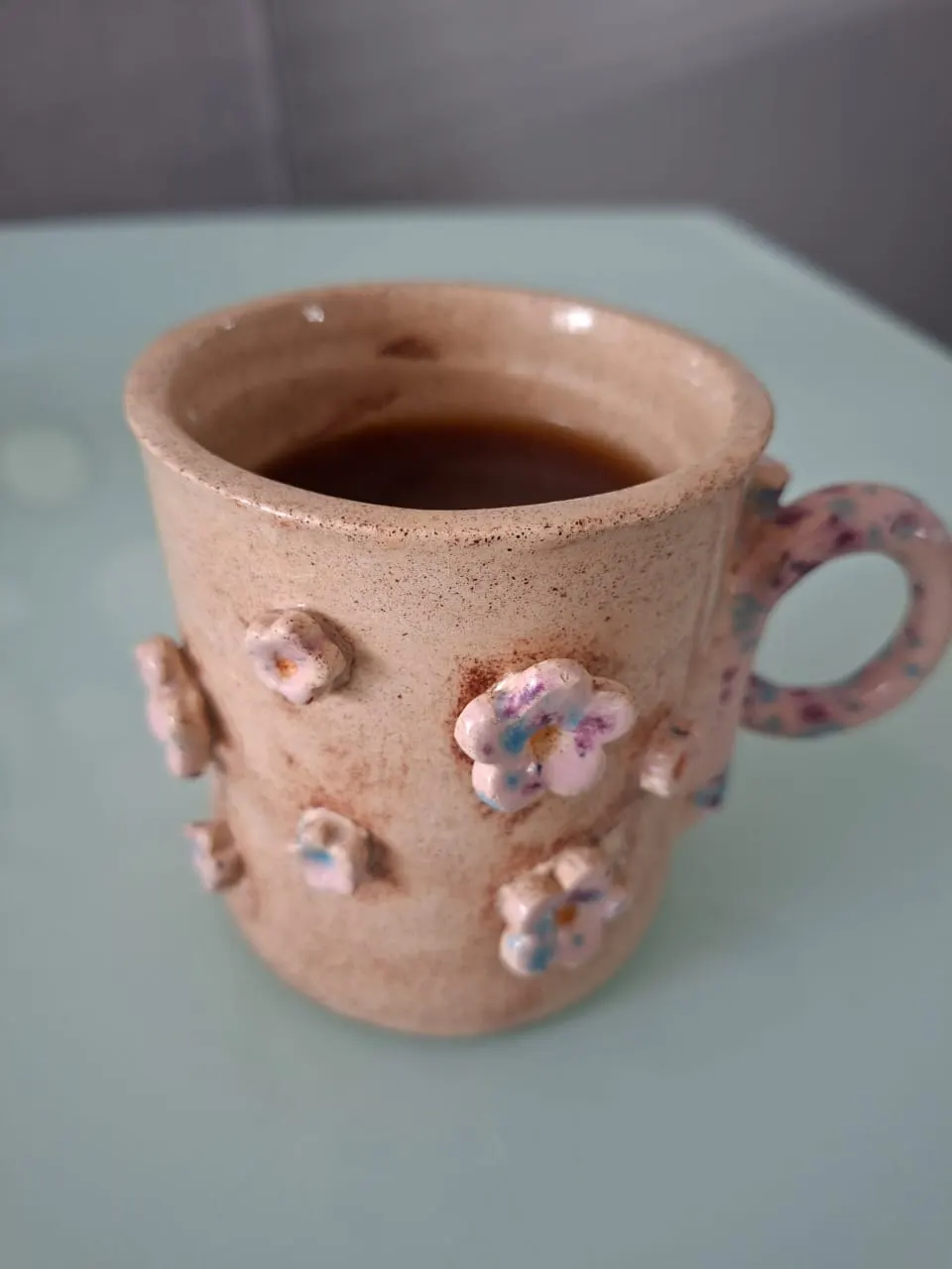 Taza de cerámica con flores en relieve y asa moteada