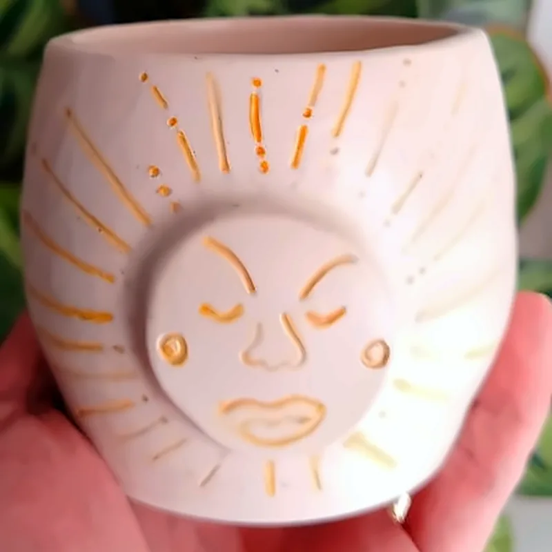 Taza de cerámica sin asa con un sol pintado