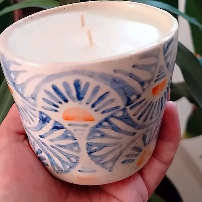 Vela en vaso de cerámica pintado con soles azules y naranjas